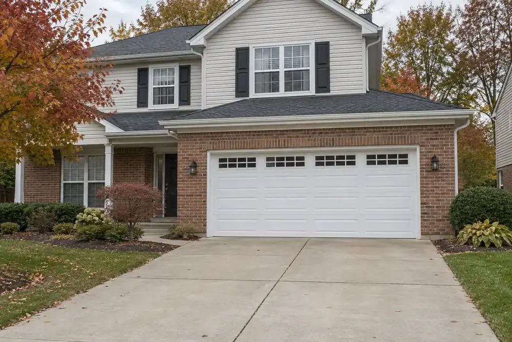 White double garage door with long panels and top windows on a brick-and-siding house
