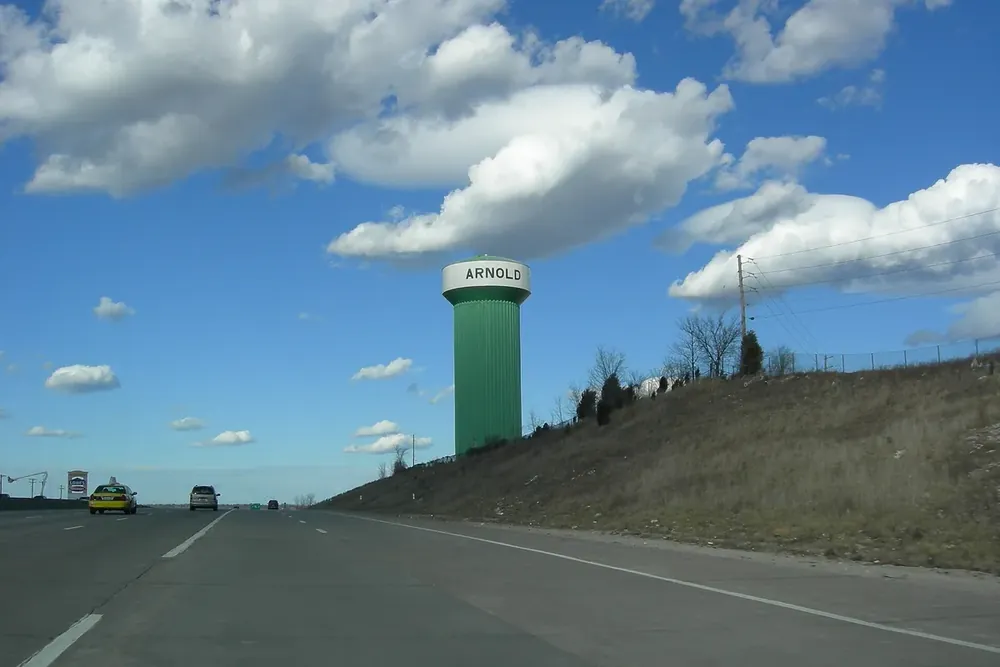 Green water tower painted with the town name beside Interstate 55 in Arnold, Missouri