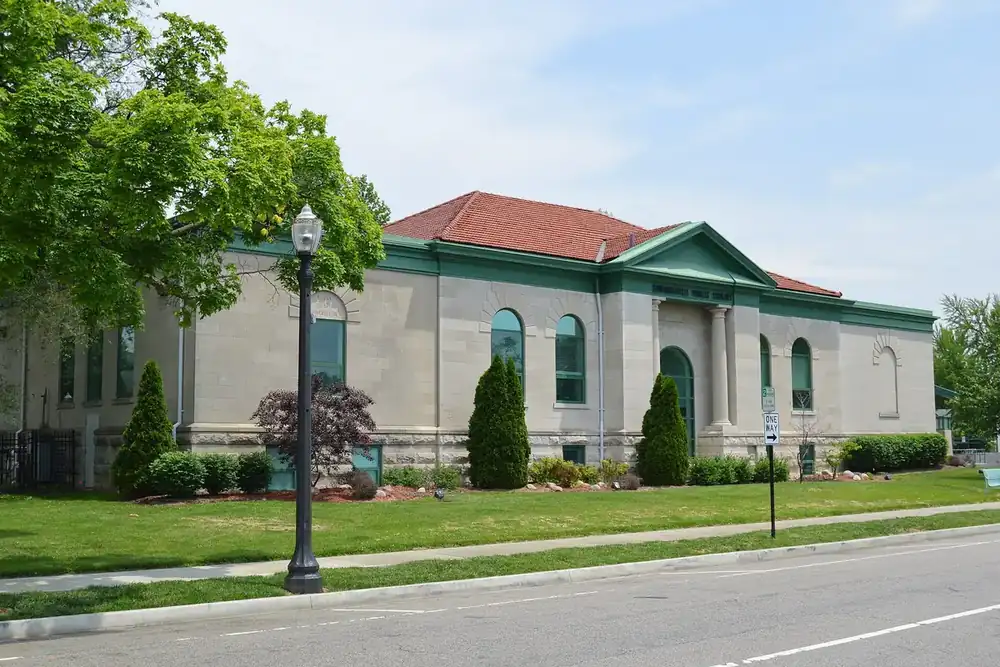 The stone Edwardsville Public Library with a red tile roof along a quiet street