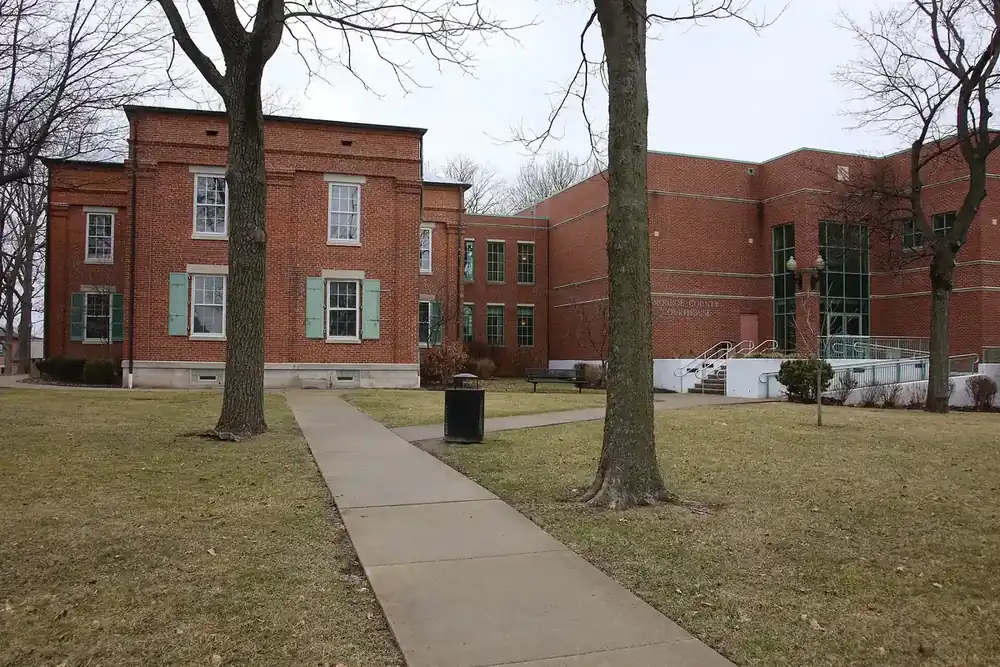 The red brick Monroe County Courthouse behind bare trees in Waterloo, Illinois